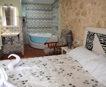 Dormitorio con bañera de hidromasaje privada junto a la cama en este acogedor hotel rural.