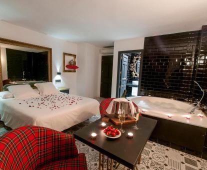 Suite Alcoba de la Reina con decoración romántica y bañera de hidromasaje privada junto a la cama.