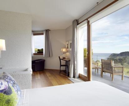 Foto de la Suite con bañera de hidromasajes junto a la cama y terraza con vistas al mar.