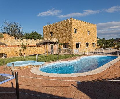 Edificio de piedra con piscina al aire libre y amplia zona exterior de este acogedor hotel rural.
