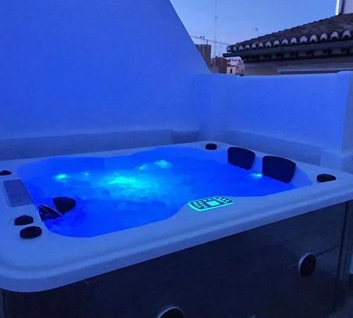 Foto del jacuzzi en la terraza por la noche con luz azul de cromoterapia en los apartamentos Granaxperience Apartamentos La Maleta