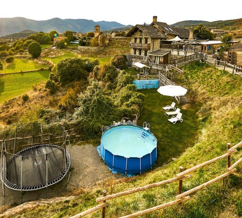 Foto de la piscina junto a la colchoneta y con la casa al fondo rodeada de jardines