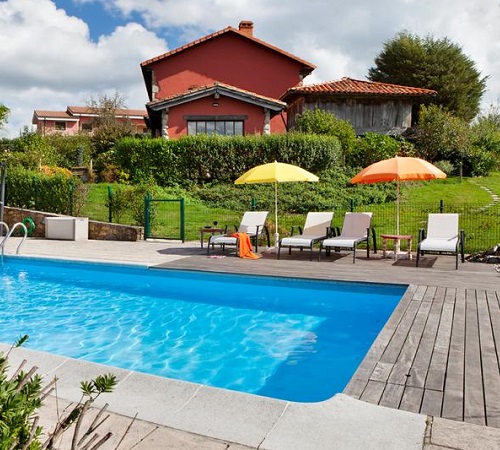Foto de la piscina y la casa al fondo rodeada de naturaleza en medio del campo en El Pedrueco Turismo Rural