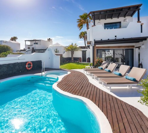Piscina ovalada en la terraza de madera frente a la casa de dos plantas en Kamezí Boutique Hotel Villas