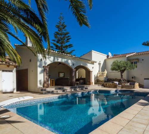 Foto del exterior de la casa en Moraira donde se ve la piscina y la terraza de la villa.