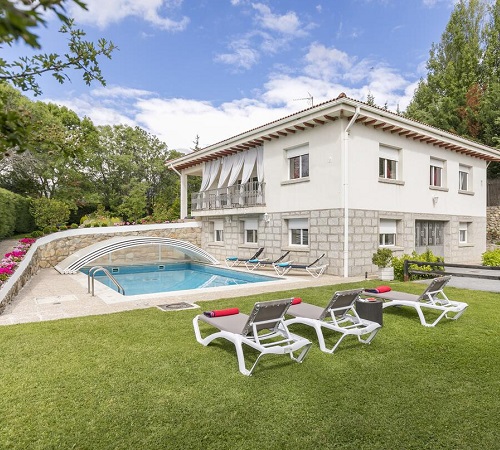 Foto del exterior de la casa El Jardín de Alameda con el jardín donde se ven unas hamacas para tomar el sol y una piscina puede cubrirse