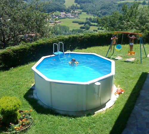 Niños jugando en la piscina que se encuentra en el jardín junto a los columpios en la casa Binahia