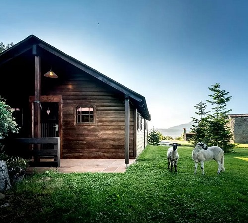 Foto de una de las cabañas de madera en Estança La Pau donde se pueden ver ovejas cerca del alojamiento