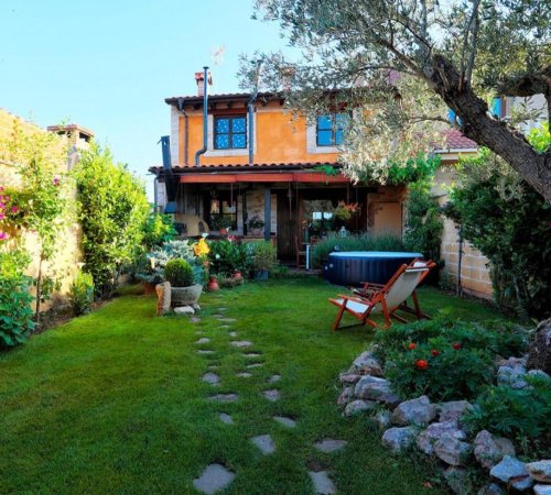 Foto del exterior de la casa rural Canalba donde se puede ver las hamacas del jardín, las mesas y el cesped que hay delante de la casa.