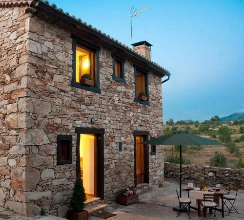Vista del exterior de la casa rural para parejas en Alojamiento & Turismo Rural Horcajuelo donde se puede ver la pared estilo rústico de piedra.