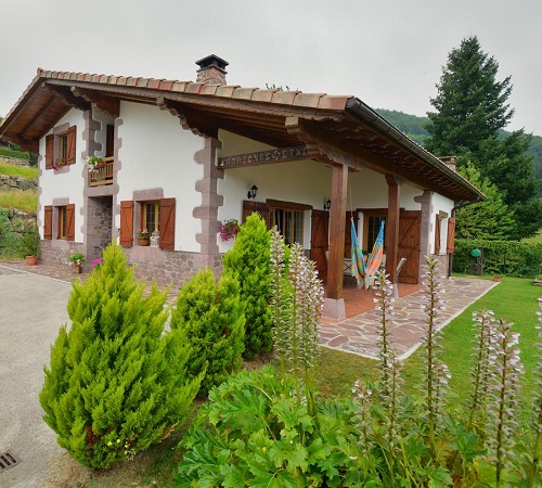 Vistas desde el jardín de Casa Rural Amazonas Etxea donde se ve el campo verde de fondo y los árboles que hay detrás de la casa rural