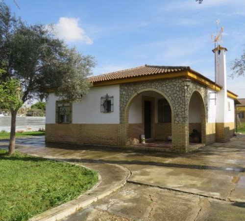 Foto desde fuera de la casa rural Chalets Aeropuerto de Sevilla donde se puede ver una casa ideal para dos personas y los jardines de alrededores