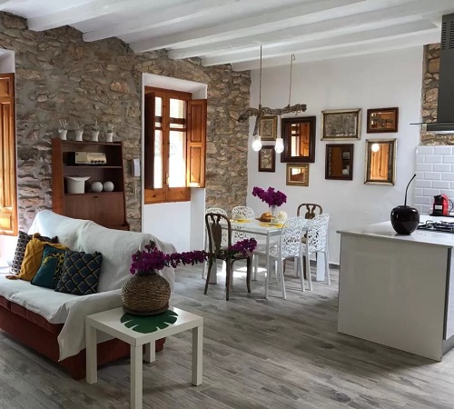 Foto del interior de la sala de estar y la cocina con decoración rústica y suelos de madera en la Casa Rural Tutu llar us turistic