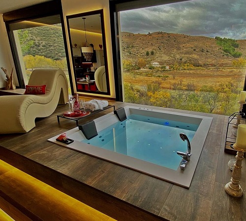 Habitación con grandes ventanales con cristal con increíbles vistas al campo desde el jacuzzi