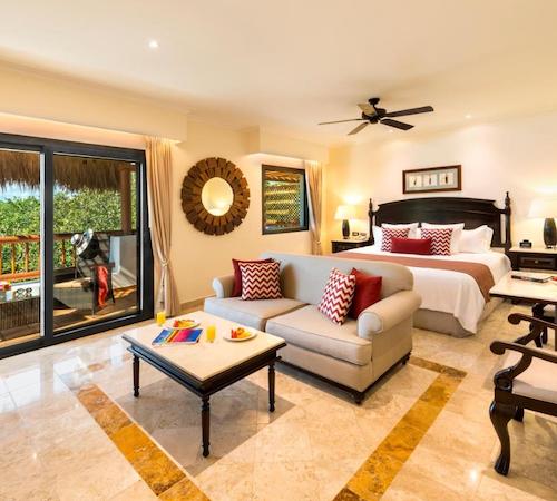 Suite del lujo con cama king, mobiliario y mesa frente a la cama, y también con una terraza con vistas a la selva en hotel Valentin Imperial Riviera Maya All Inclusive