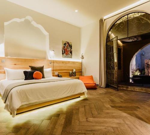 Foto de la suite con la cama elevada sobre el suelo con luz saliendo de debajo y la terraza amueblada al fondo en Tá Hotel de diseño