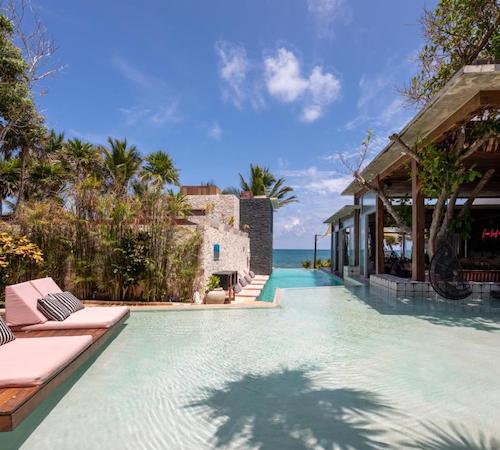 Piscina poco profunda con asientos y camas en los bordes frente a un techado donde se encuentra el bar con vistas al mar en el hotel Mi Amor a Colibri Boutique Hotel - Adults Only