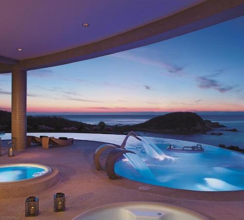 Piscina con chorros de hidromasaje juntos a dos bañeras de hidromasaje con vistas al mar y unas islas en el hotel Secrets Huatulco Resort & Spa