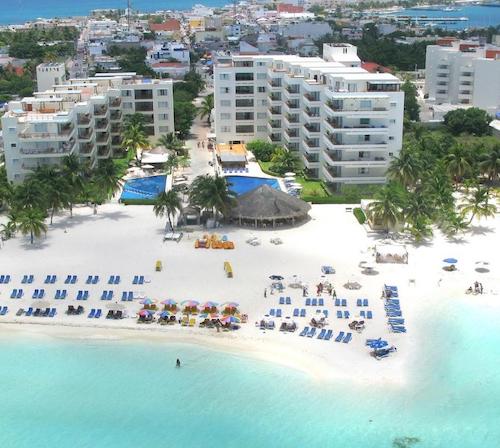 Vista desde el cielo de varios edificios del hotel Ixchel Beach alrededor de la gran piscina con vistas al mar y cerca de la playa de arena blanca