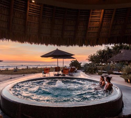 Foto de unas chicas en un enorme jacuzzi circular con vistas al mar bajo un techado en el hotel Samora Luxury Resort