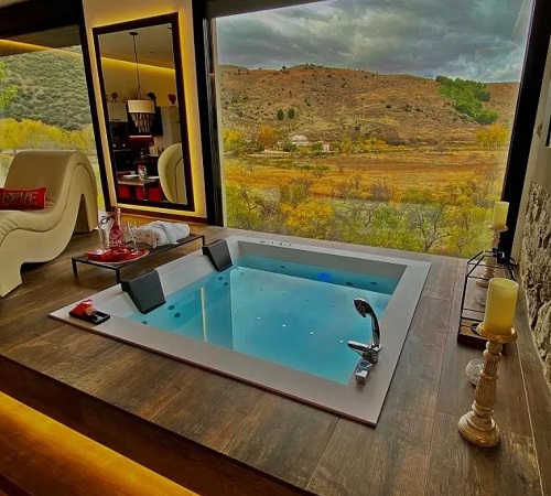 Jacuzzi a ras de suelo junto a la enorme ventana con vistas al campo en Suite Rural Carenas