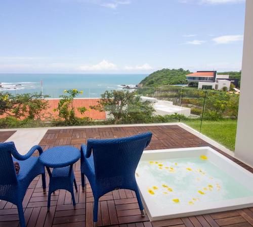 Jacuzzi privado a ras del suelo en la terraza junto a una mesa y dos sillas azules en la Suite Junior Doble con bañera de hidromasaje del hotel Secrets Huatulco Resort & Spa