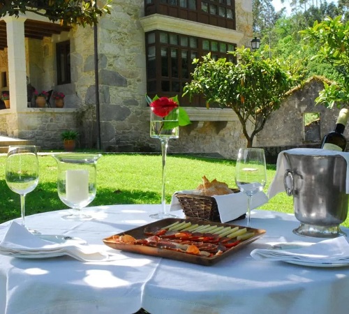 Foto de la mesa para desayunar en el jardín con el hotel Torre do Rio al fondo