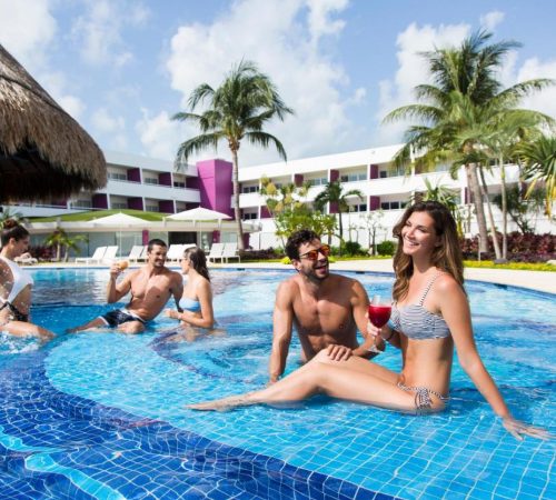 Una pareja y un grupo de amigos en la piscina cerca del bar que se encuentra en el Hotel The Tower by Temptation Cancun Resort - All Inclusive - Adults Only