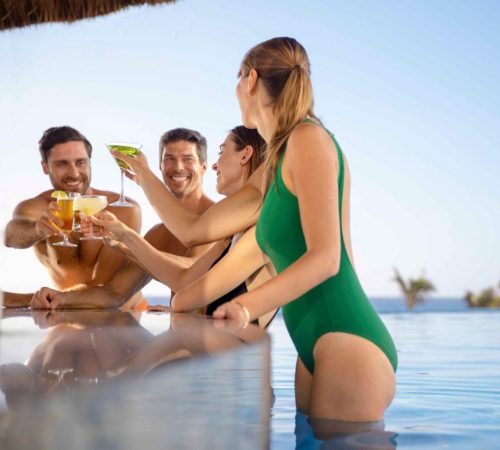 Dos chicas y dos chicos en la barra del bar que se encuentra dentro de la piscina en el Hotel Le Blanc Spa Resort Cancun Adults Only All-Inclusive
