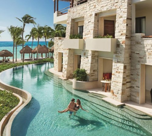 Una parejas disfrutando en la piscina que rodea el edificio donde se alojan y que se accede desde unas escaleras que llegan directamente desde la puerta de su apartamento