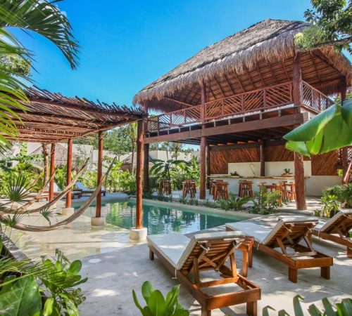 Foto de la piscina, unas tumbonas y paraguayas junto al bar bajo un techado rústico en Hotel Zenses Wellness and Yoga Resort - Adults Only