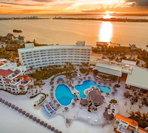 Vista aérea del hotel Grand Park Royal Cancún de Cancún donde se ve la playa, las piscinas y la puesta de Sol