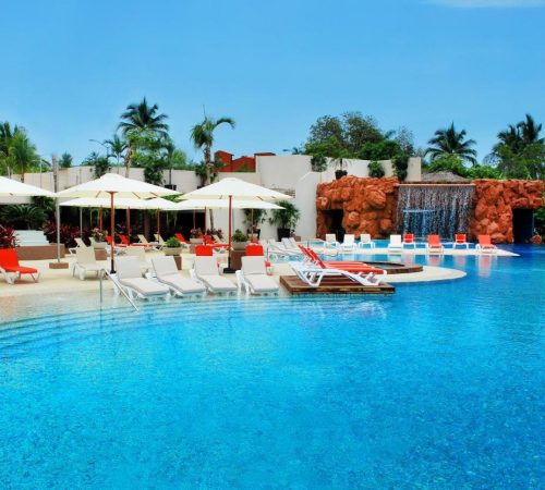 Foto  de la piscina con las tumbonas junto al agua y sombrillas para tomar el sol en Azul Ixtapa Grand All Inclusive Suites