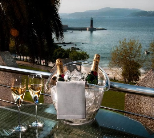 Foto de la mesa en la terraza de Hotel Pazo Los Escudos Spa & Beach con vistas al mar con un botella de Cava en la mesa.