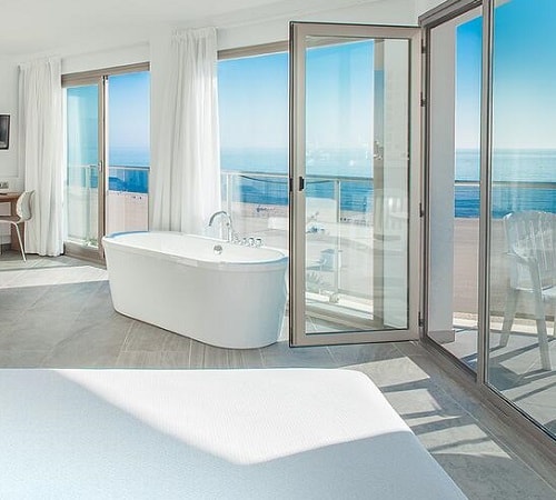 Suite del hotel RH Bayren Hotel & Spa con bañera y terraza con vistas al mar desde la cama de la habitación