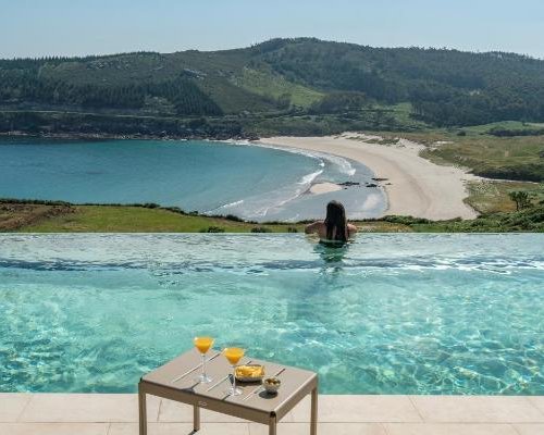 Mujer en la piscina mirando las vistas a la playa y la costa desde el Parador Costa da Morte