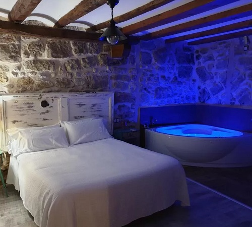 Foto del dormitorio del apartamento Deluxe con bañera de hidromasaje junto a la cama en El Racó de Valderrobres