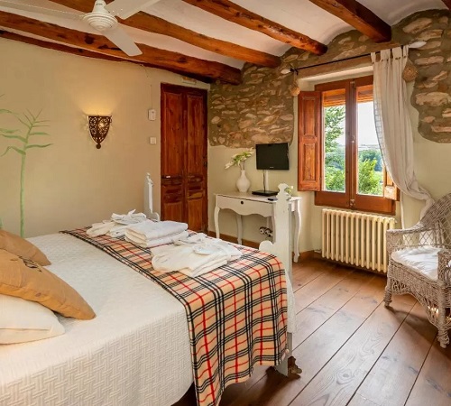 Decoración rústica de la suite ideal para una escapada de San Valentín en el campo con vistas a la montaña en un hotel rural.