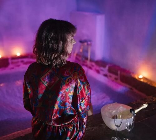 Foto de la casas romántica en Aldea Ecorural donde se encuentra un jacuzzi con una mujer junto al borde y con una botella de champagne