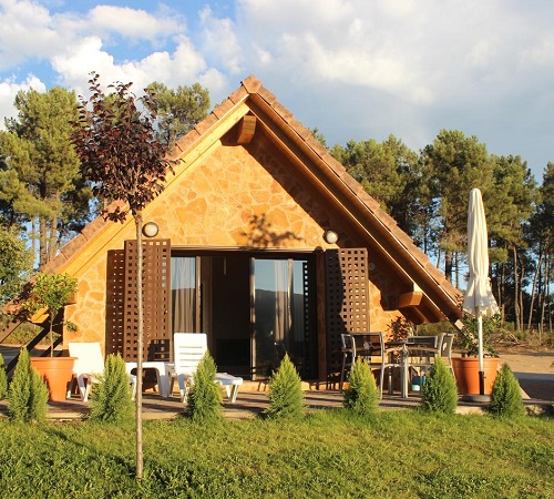 Cabaña para con techo triangular rodeada de jardín en el Complejo Rural La Coronilla