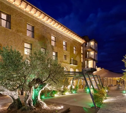 Vista del Hotel Palacio Tondón del exterior donde se puede ver el edificio de piedra y rústico junto a los jardines.