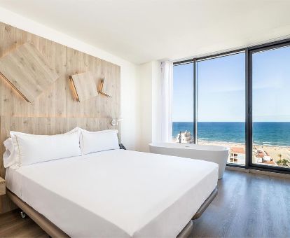 Una de las modernas habitaciones con bañera junto a la cama y vistas al mar de este moderno hotel.