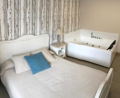 Dormitorio con bañera de hidromasaje privada junto a la cama de una de las acogedoras habitaciones del establecimiento.