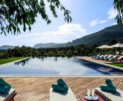 Hermosa piscina exterior rodeada de tumbonas y vegetación con vistas a la naturaleza que rodea este romántico hotel.