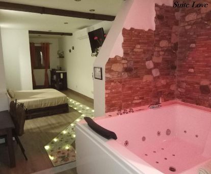 Dormitorio con un fabuloso jacuzzi privado cerca de la cama de este apartamento independiente.
