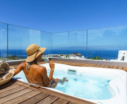 Mujer disfrutando del jacuzzi al aire libre de la suite de dos dormitorios con vistas parciales al mar.