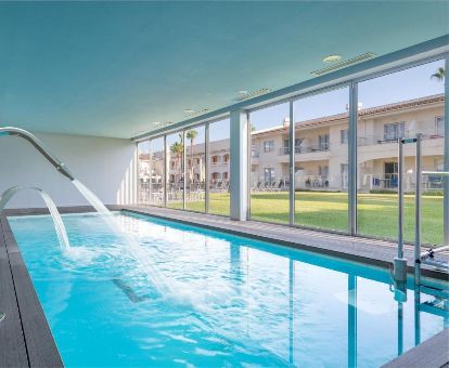 Piscina cubierta con chorros de hidroterapia y vistas al exterior del spa del hotel.