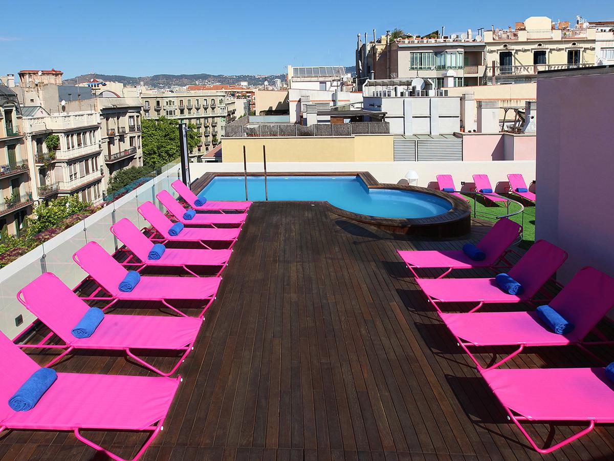 Foto de la piscina en la azotea, con el mobiliario de color rosa, la piscina y con vistas al eixample de Barcelona donde puedes pasar unos momentos geniales con tu pareja.