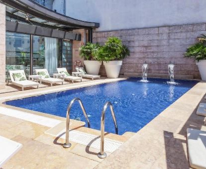 Agradable terraza con piscina y solarium con tumbonas de este moderno hotel para parejas.