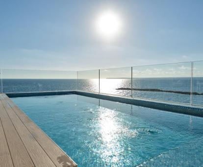 Foto de la piscina en la terraza de la azotea con solarium y vistas panorámicas al mar.